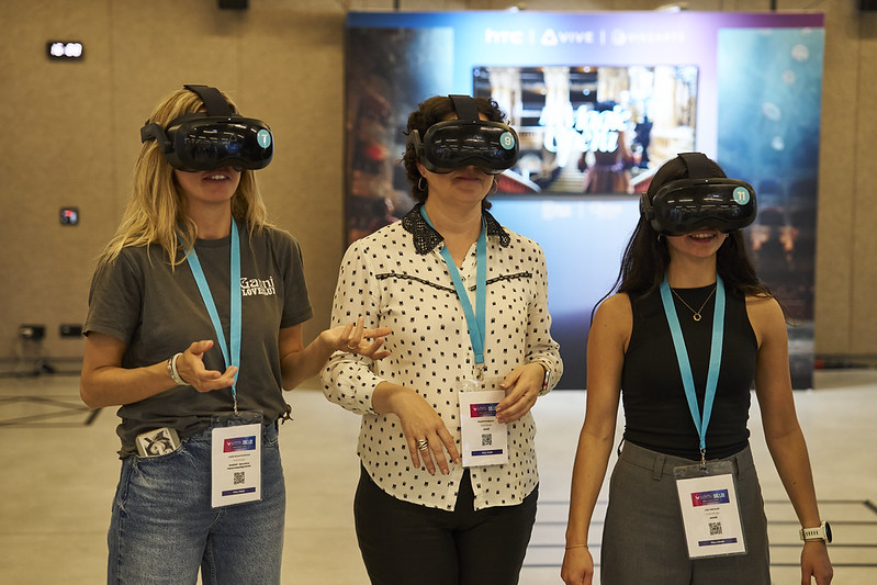 Trois visiteuses testent une expérience VR multijoueur sur l’espace HTC VIVE